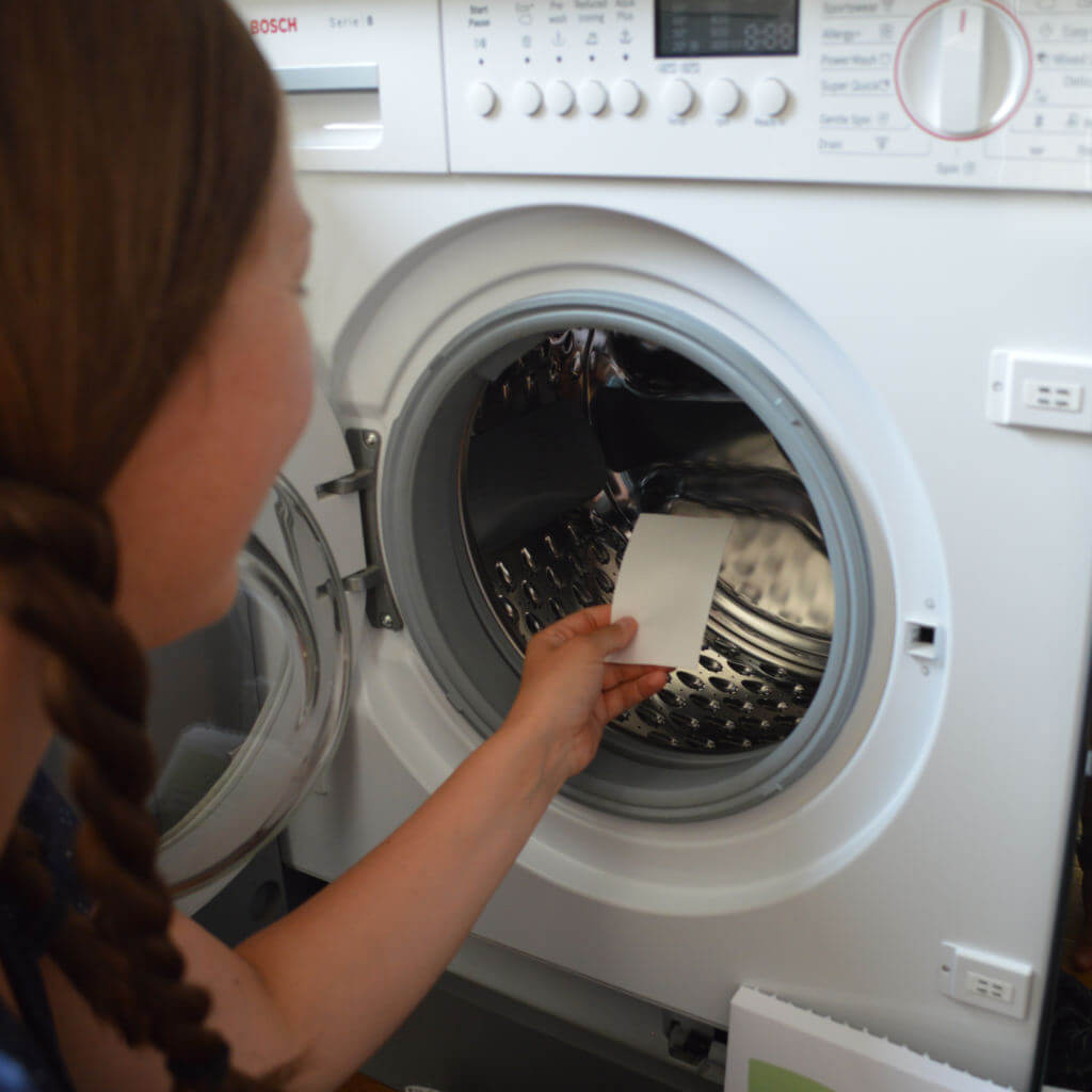 Woman putting Reco Laundry Detergent Strip into washing machine
